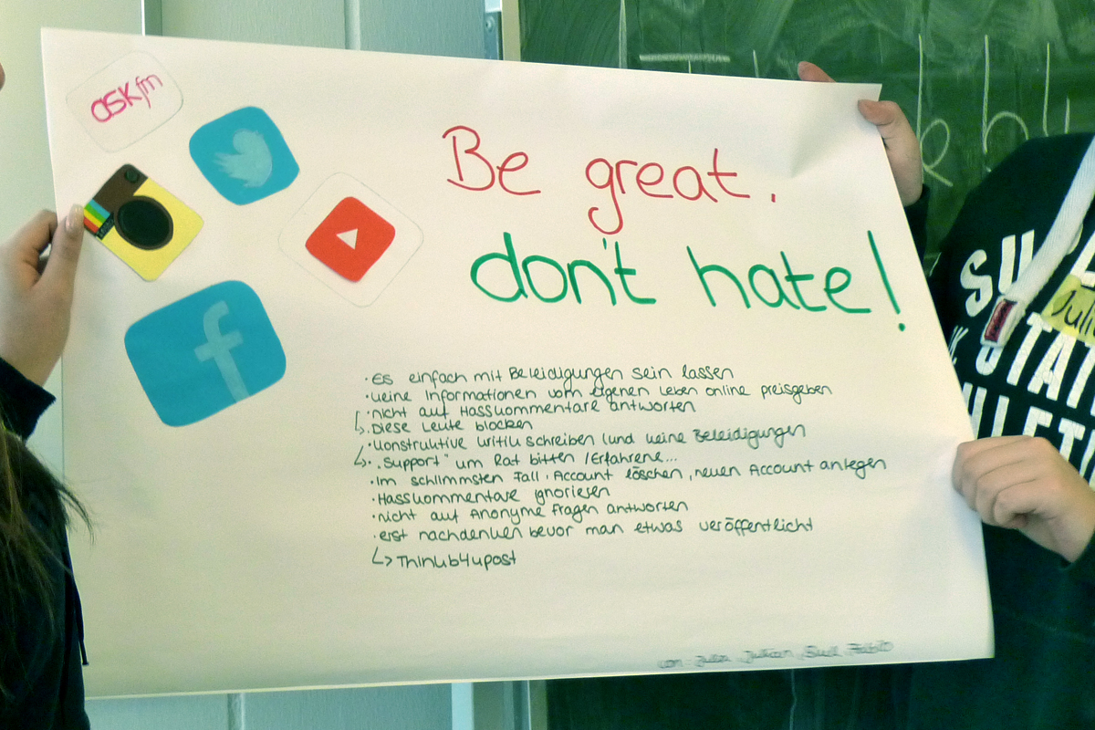 2 Schüler halten ein Poster mit Verhaltensweisen gegen Hate Speech 