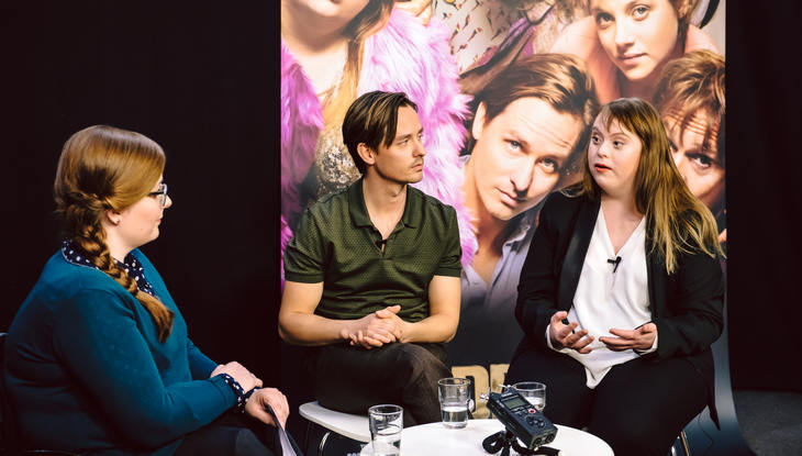 Judyta Smykowski im Gespräch mit einem Mann und einer Frau vor einem Filmplakat