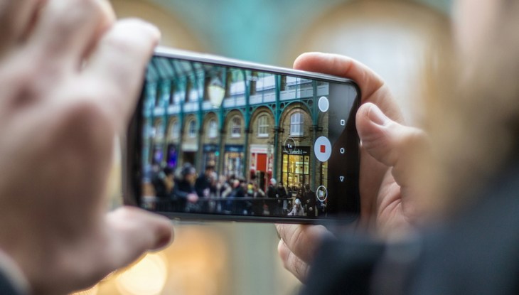 Ein Smartphone filmt im Querformat Menschen auf einer Demo.