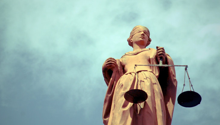 Eine Statue der Justita steht vor blauem Himmel.