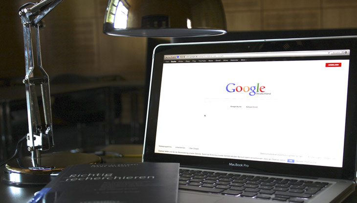 Auf einem aufgeklappten Notebook ist die Google Startseite zu sehen.